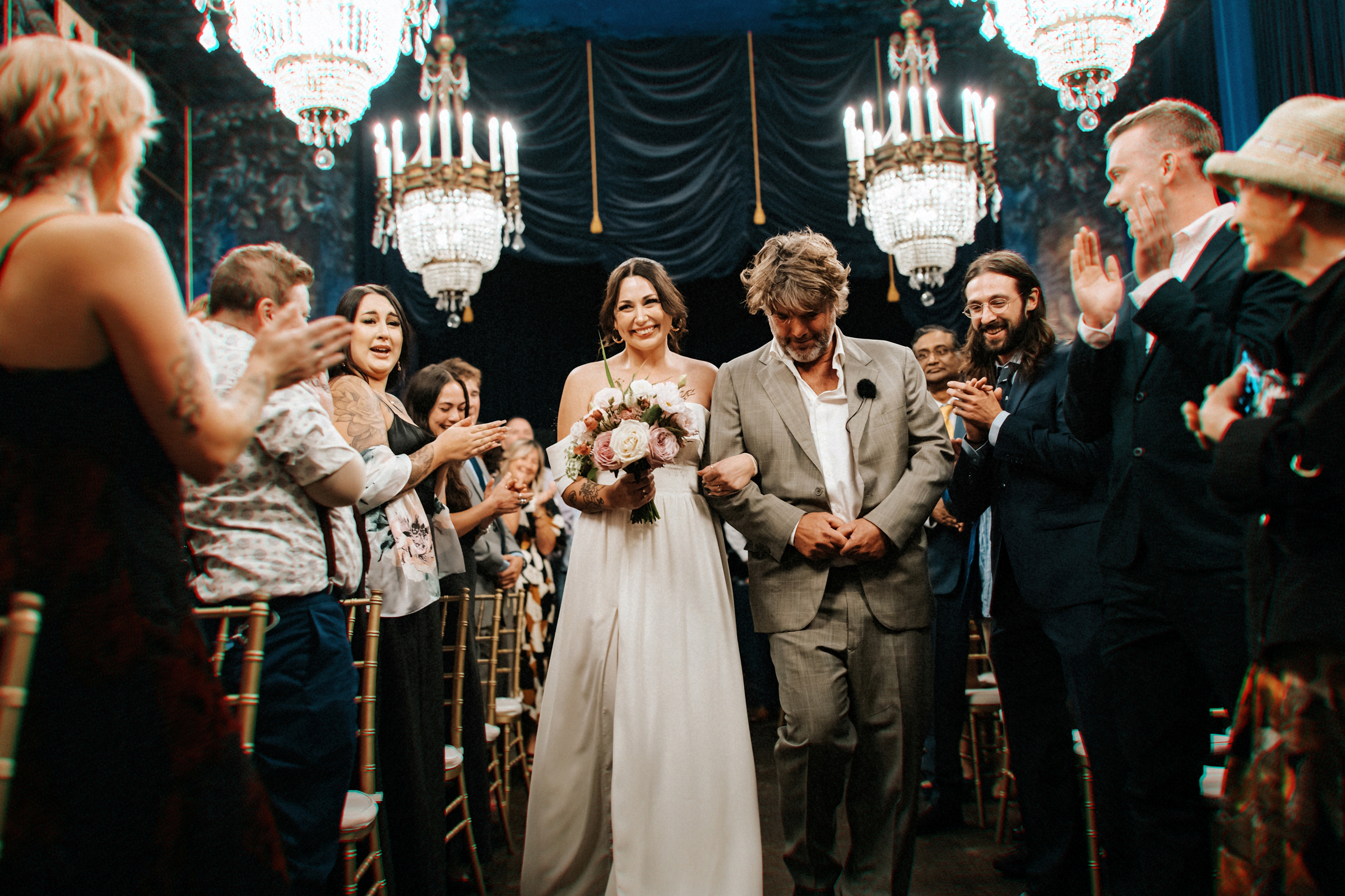 A Bride walking down the aisle with her father, inside a fun, alternative wedding ceremony space