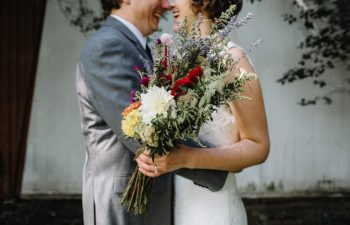 bride and groom laughing while holding bouquet