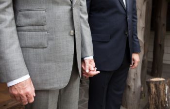 two men holding hands on their wedding day