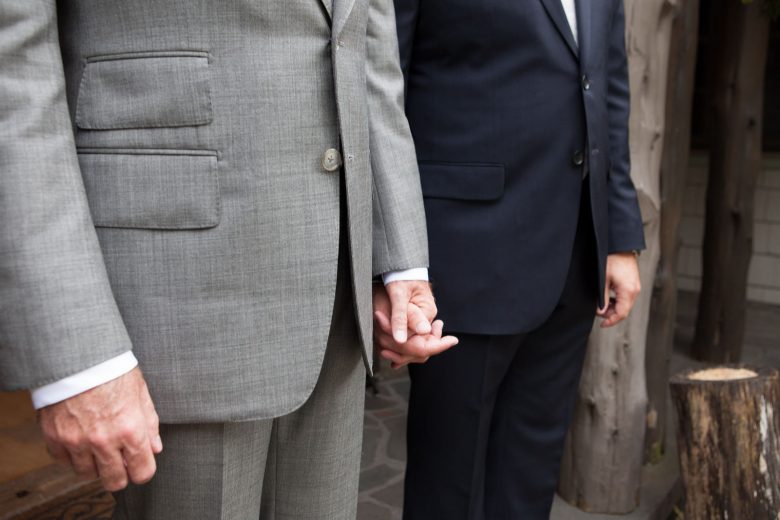 two men holding hands on their wedding day