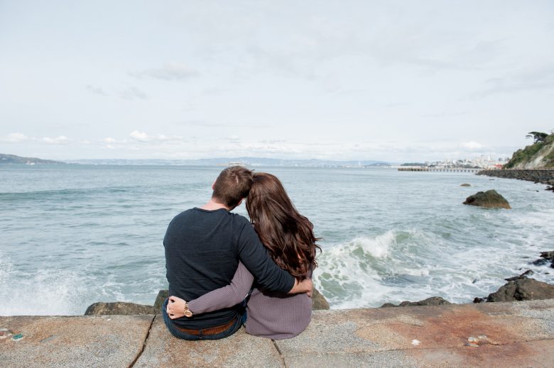 man and woman embracing while looking at the ocean