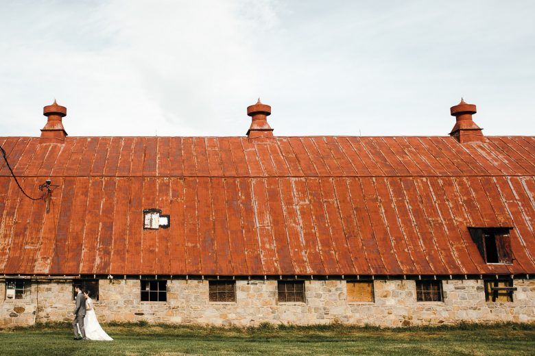 bride and groom walking in front of barn