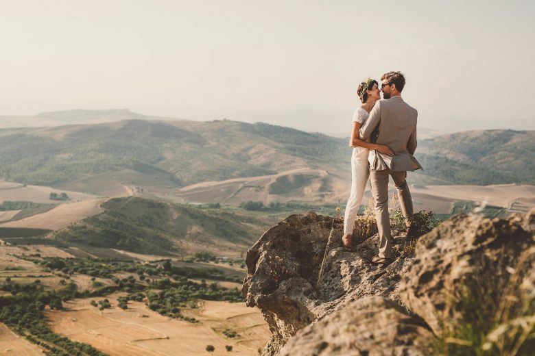 bride and groom standing on a hill