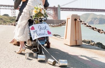 bride and groom riding on motorcycle with just married sign