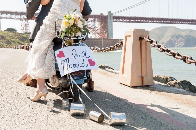 bride and groom riding on motorcycle with just married sign