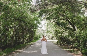 bride standing alone under trees