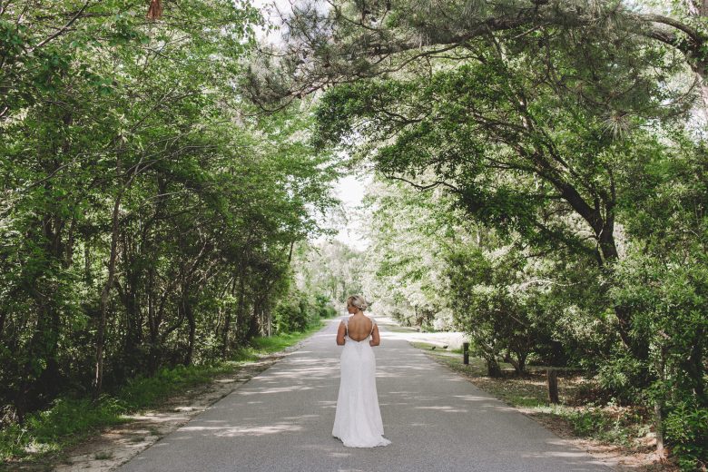 bride standing alone under trees