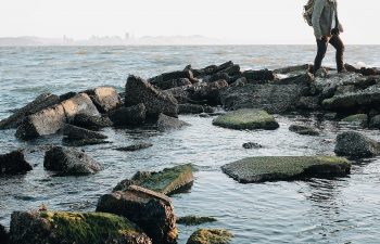 person walking on rocks near the ocean