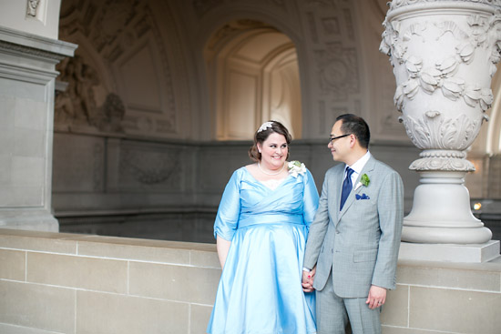 woman in blue wedding dress holds hand of man in grey suit at San Francisco City Hall