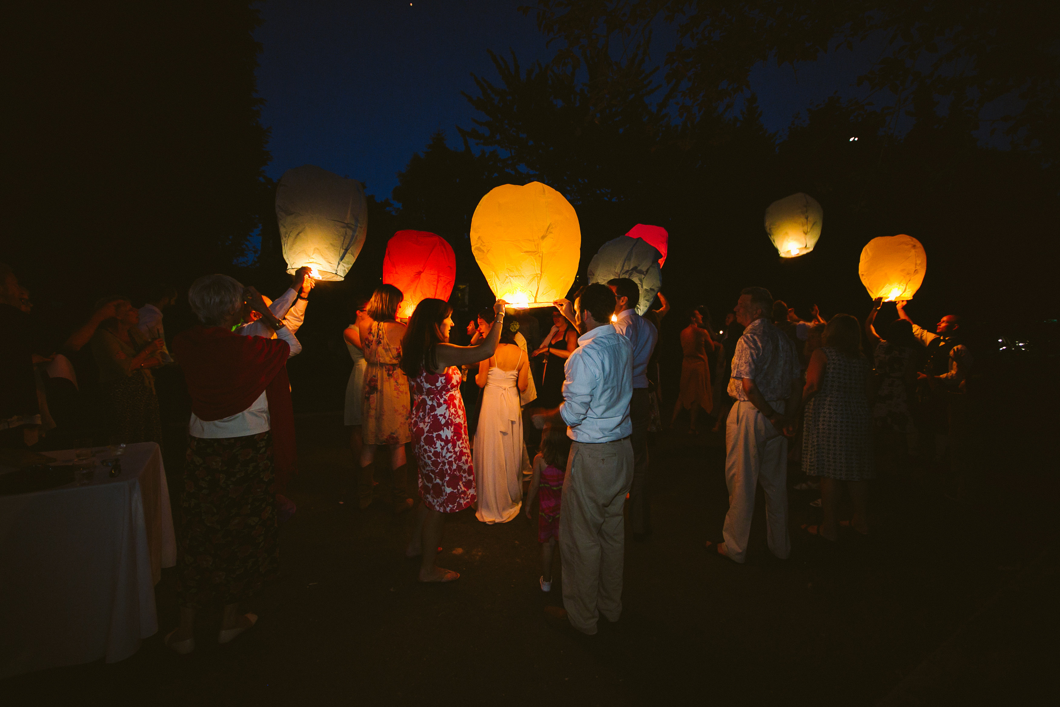 backyard wedding guests holding lit-up paper lanterns
