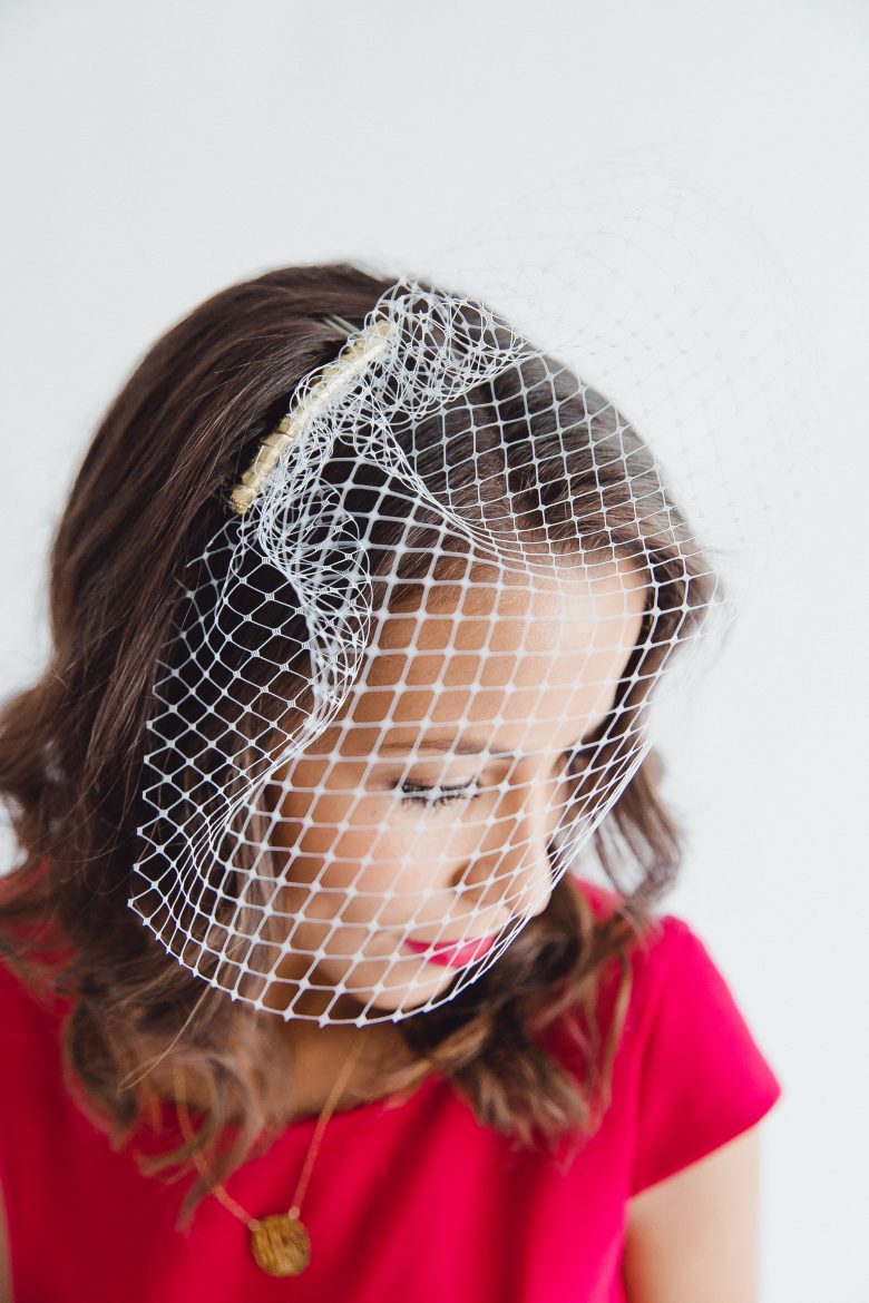 Bride in a red dress looking down in a DIY birdcage veil