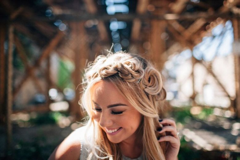 Girl smiling with mini boho buns under train bridge | A Practical Wedding