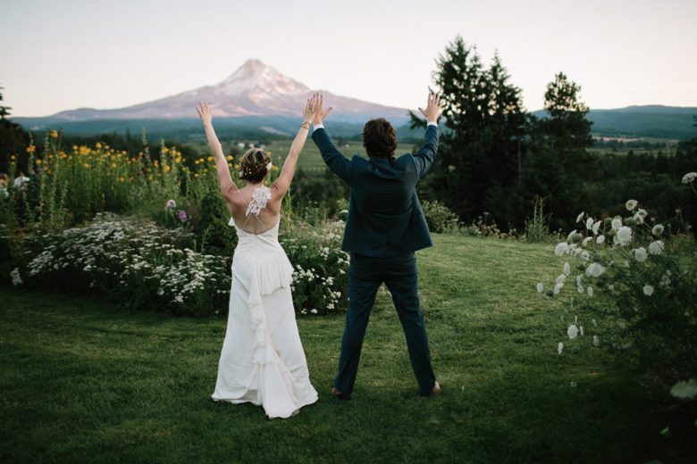 Bride and groom side by side plugging in to nature with hands up and legs apart