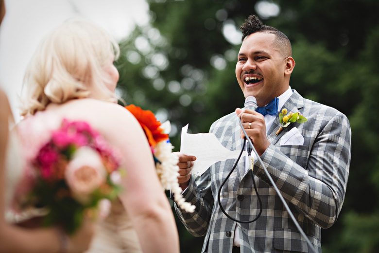 Man holding microphone and paper while laughing | A Practical Wedding