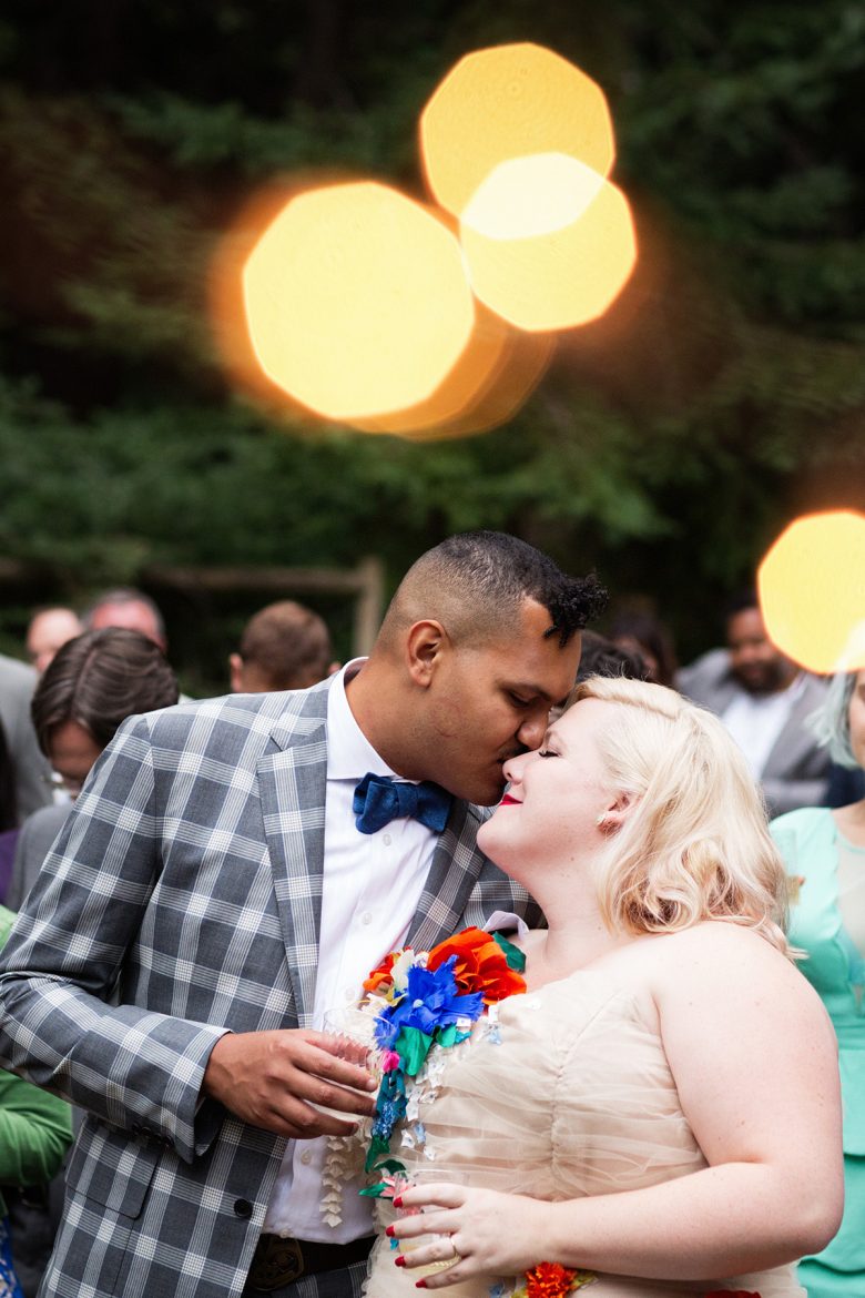 Man in plaid suit kissing blonde woman in strapless dress's forehead | A Practical Wedding