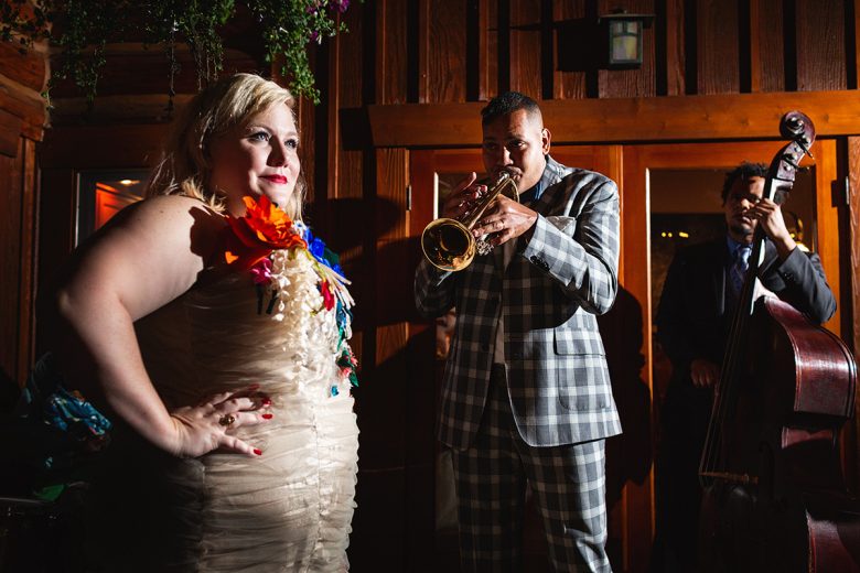 Girl in flower dress looking amused as men play trumpet and standup bass | A Practical Wedding