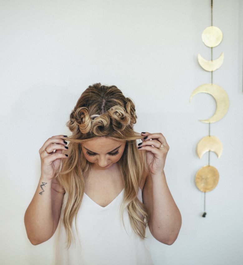 Girl in a white room with gold moons looking down with twisted hairstylw | A Practical Wedding