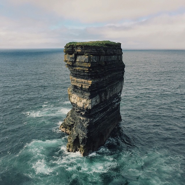 landscape photo of towering rock in ocean