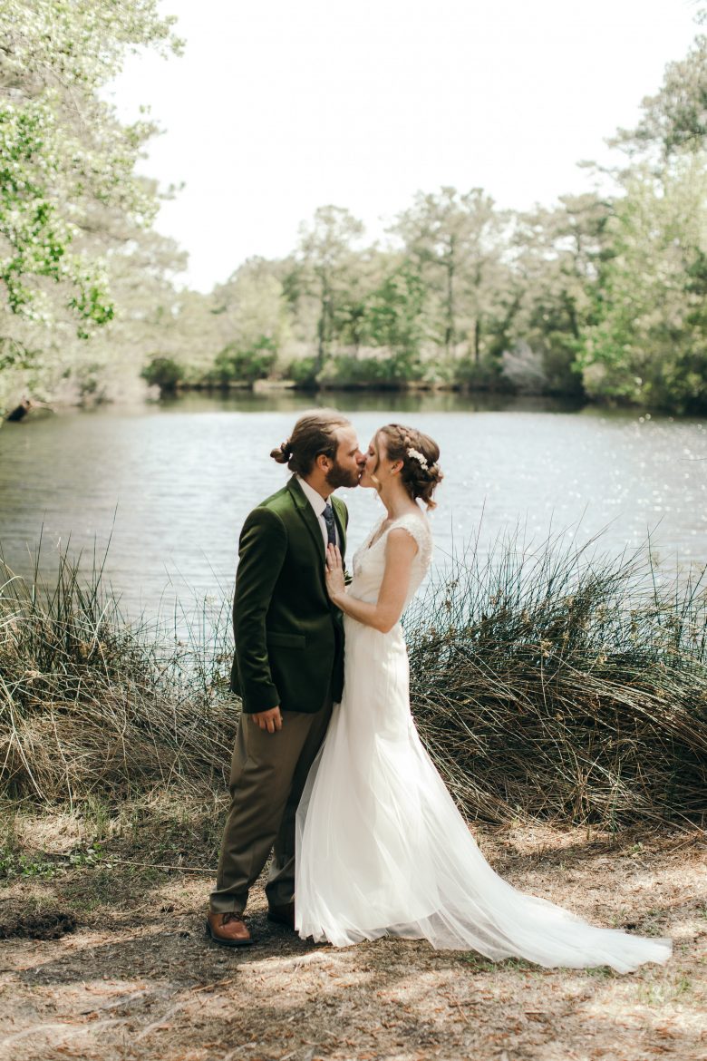 married couple kissing outside in front of a pond