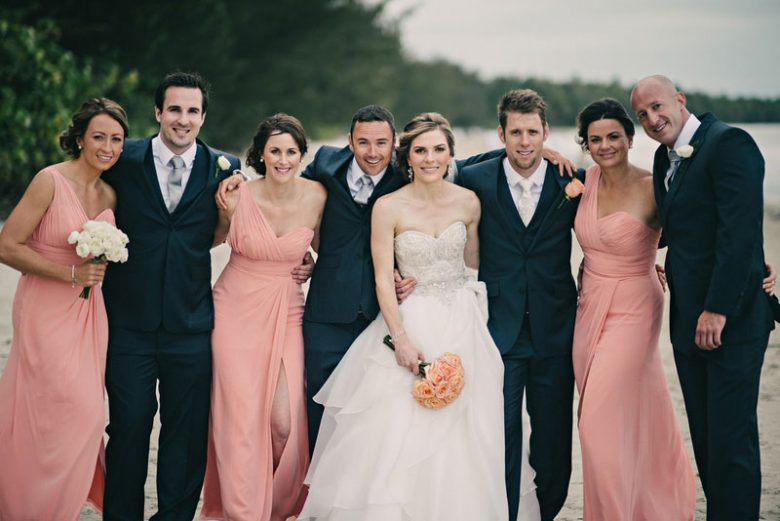 Bridesmaids in pink dresses and bridal party on beach