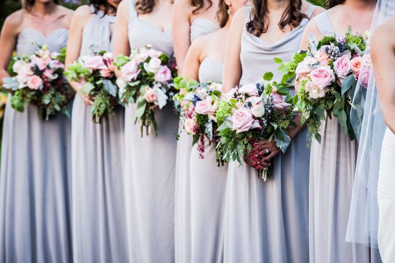 Bridal party in lavender wedding dresses and holding flowers