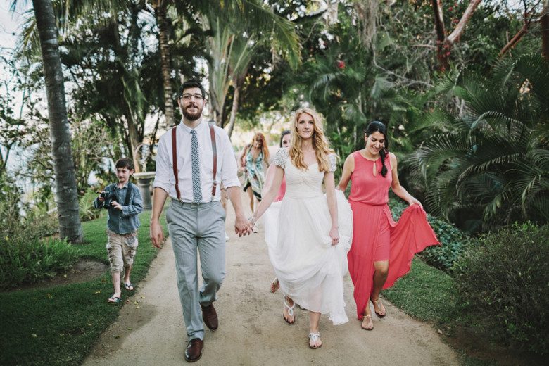 Bride and groom walking in a tropical area with friends behind them