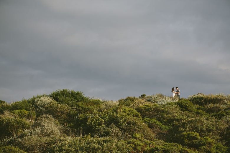 bride and groom standing on green hillside