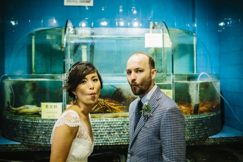 bride and groom standing in front of lobster tank
