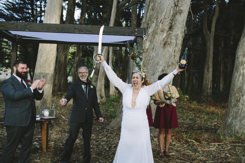bride holding a sword and bottle of wine