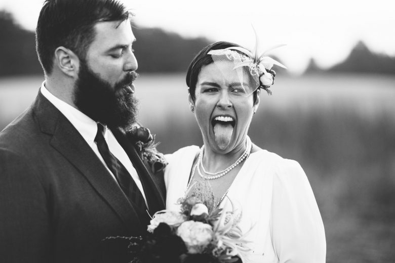 black and white photo of bride and groom sticking out their tongues