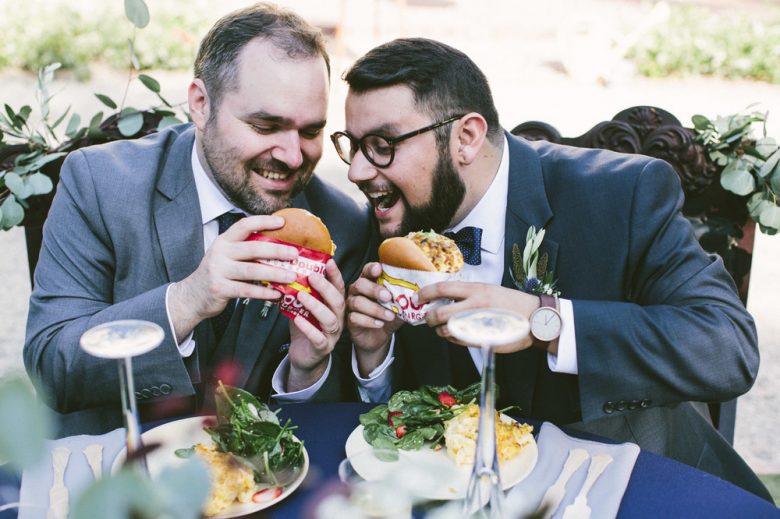 two grooms eating burgers on their wedding day