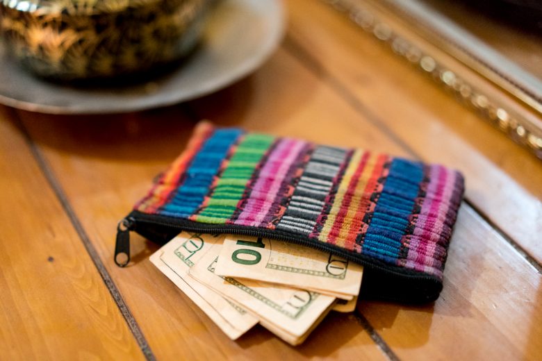 Multi-colored textile wallet with ten dollar bills sticking out
