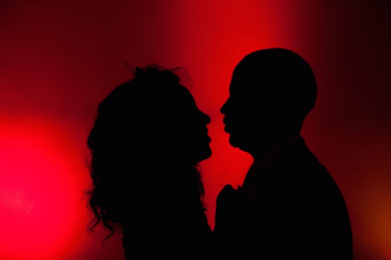 bride and groom silhouetted against red background