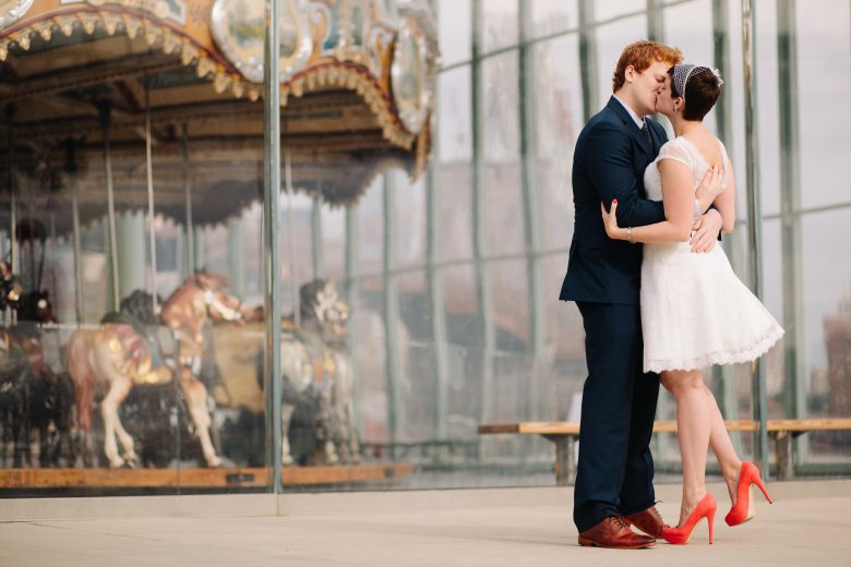 Bride and groom kissing in front of carousel 