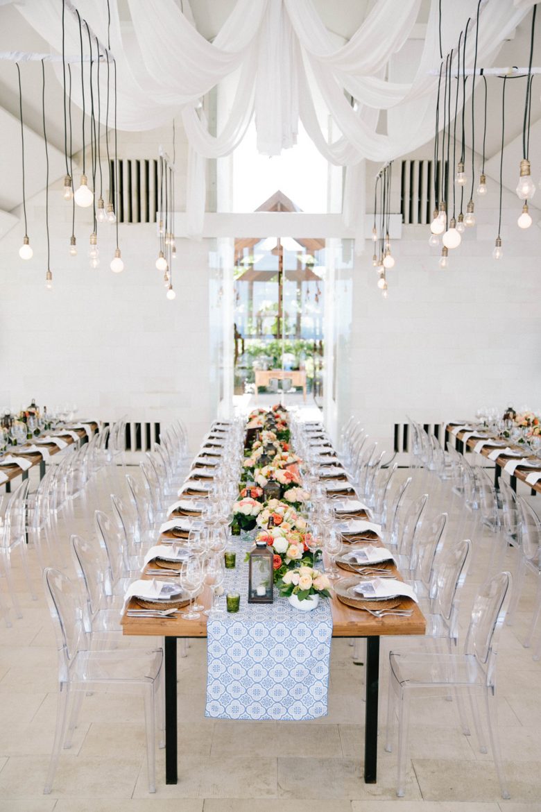 wedding venue with farm tables, pendant lighting, and clear ghost chairs