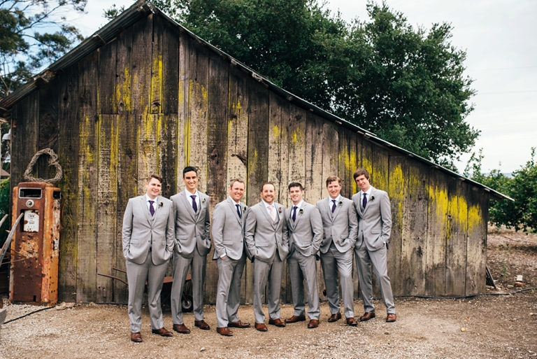 wedding party in grey suits in front of a barn