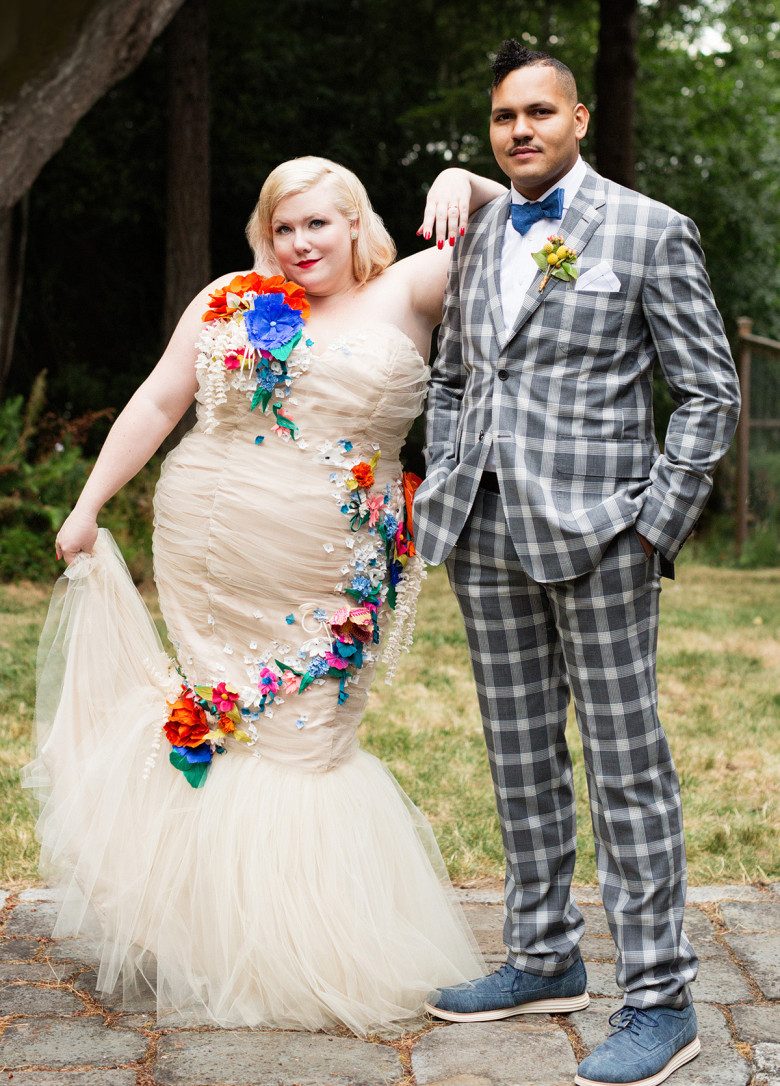 lindy west in her wedding dress covered in flower with partner aham in checked suit