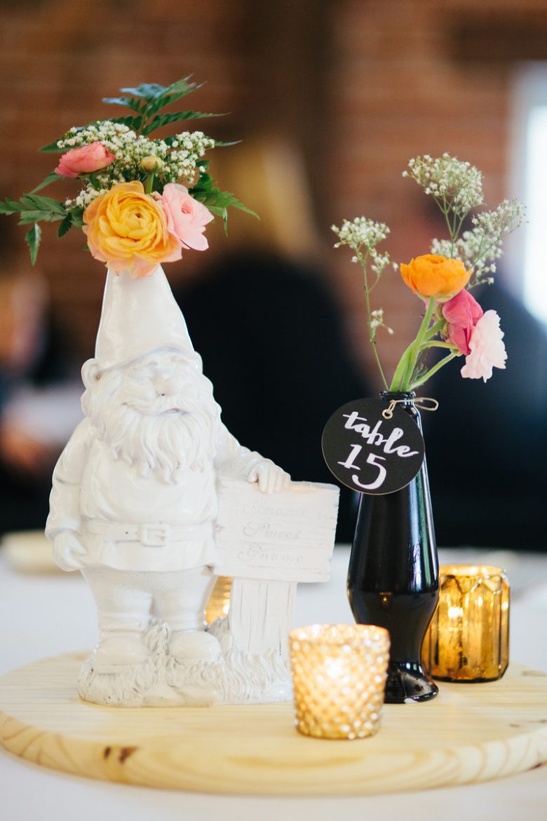 wedding centerpiece make with black vase, gold votives and white gnome sculpture