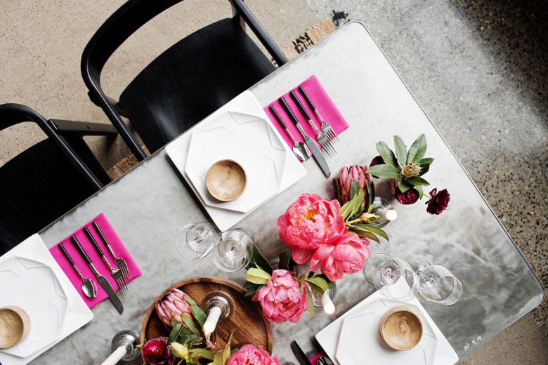 Metal table set with big pink flowers and pink accented settings and black chairs