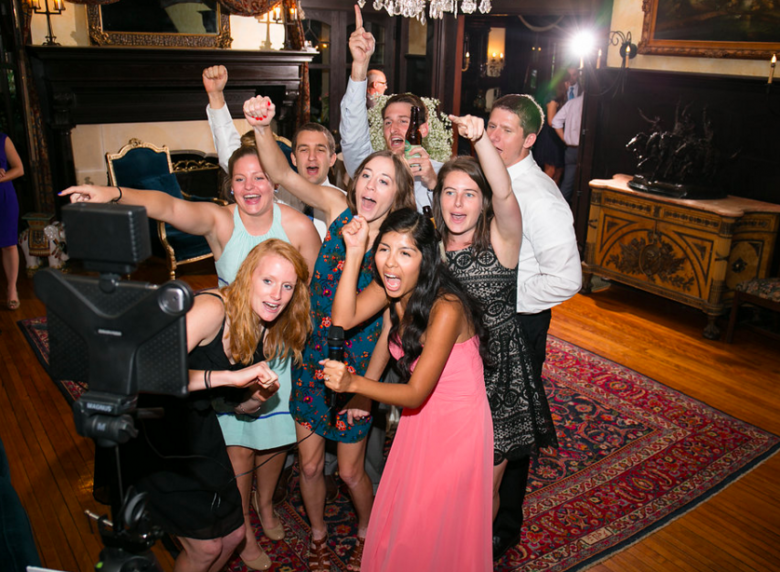 group of people giving a toast in front of video camera and ipad at a wedding