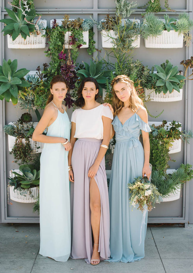 three women in joanna august mismatched pastel bridesmaid dresses