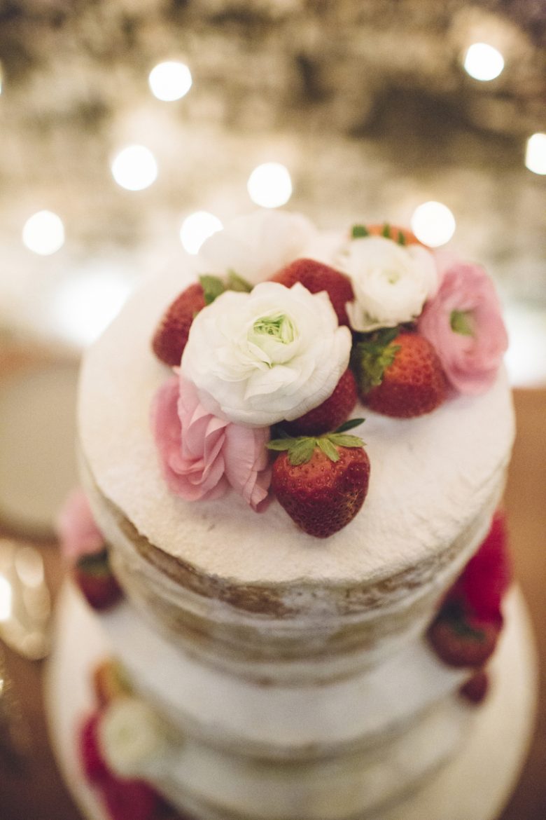 wedding cake topped with strawberries and flowers