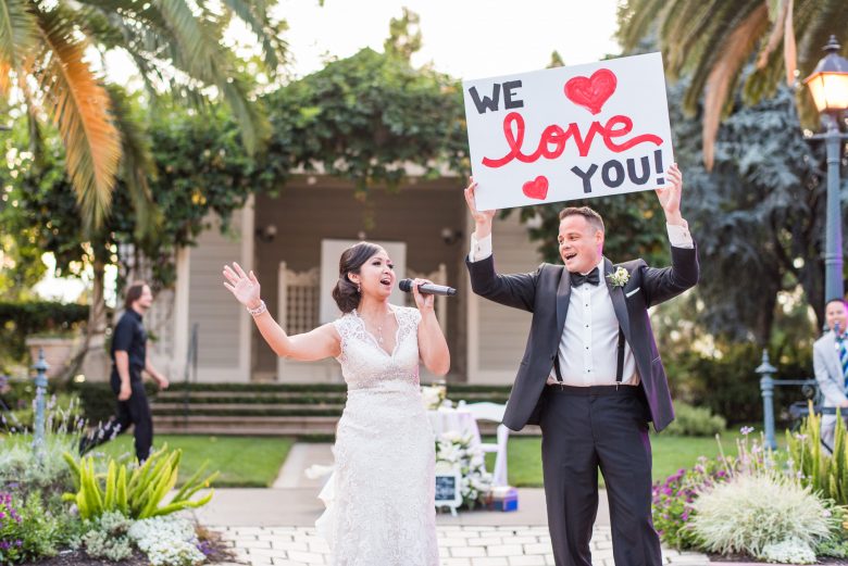 married couple holding a microphone and "we love you" sign