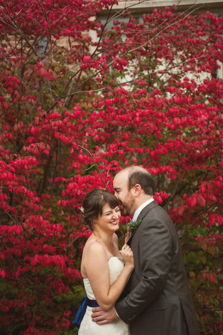 bride and groom laughing in front of pink flowers