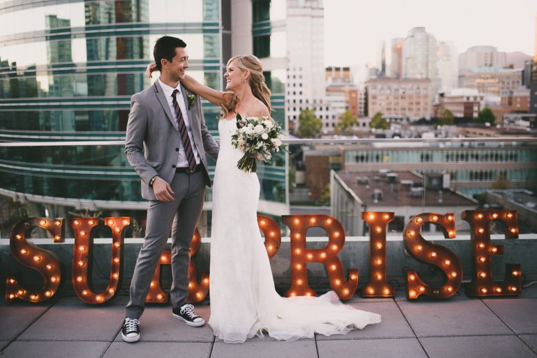 Married couple in front of surprise wedding sign on rooftop
