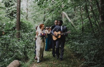 groom playing acoustic guitar and walking with bride