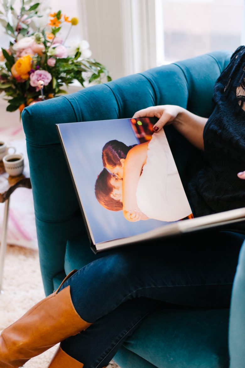 woman looking at Shutterfly album in velvet chair