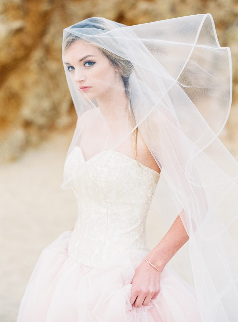 bride with veil and white corset in front of rock