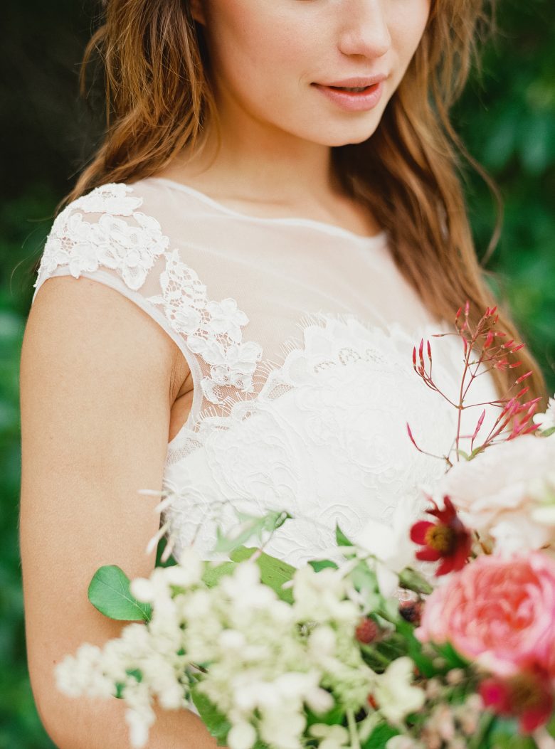 close up of white lace shirt on a brunette and light flowers