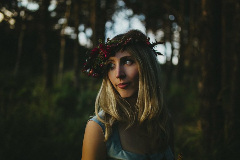 Woman wearing floral crown standing in forest
